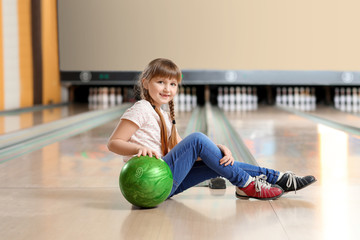 Fototapeta premium Little girl playing bowling in club