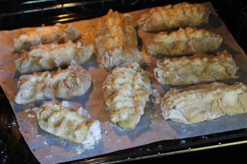Stage of preparation of Karelian pies -Pirakka. Pies are located on a wooden board, being filled ready for baking. Dish of national cuisine - piirakka. Close-up.