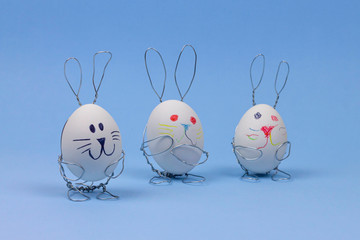  Easter decorations on a blue background. Eggs in rabbit stands. Happy Bunny toys. The child...
