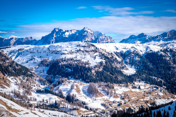 View of coniferous forest and mountains from a chair lift on a sunny winter day. Ski resort Arabba in Dolomites mountains. Passo Pordoi pass. , Italy