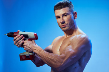 Fototapeta na wymiar Athletic man with a muscular body inflated screwdriver building lifestyle