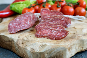 Fuet fresh and sliced on the natural wooden kitchen board closeup. Delicious natural healthy food.