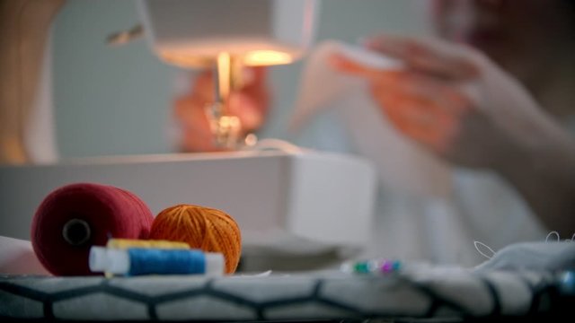 Young woman designer putting pins in the white cloth and starts sewing