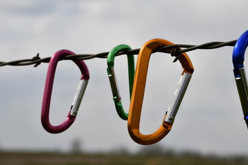 Carabiners Hanging on a Strand of Barbed Wire