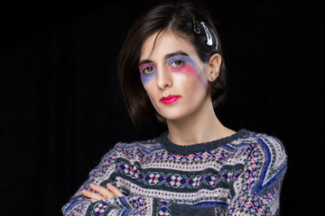 Female with creative make up and colourful sweater posing in studio. Fashion model in studio shoot. 