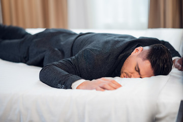 Close-up of a young man in suit sleeping on a bed