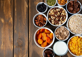 various cereals, nuts and dried fruits on wooden surface