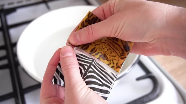 The women's hands in the kitchen in the process of painting Easter eggs over a bowl of boiling water tear a plastic sticker with an animal print of zebra.