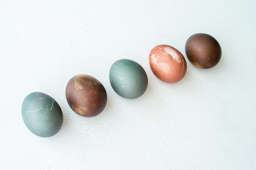 Collection of painted eggs on white stone   backround, copy space, happy easter concept. Natural colorful egg, pastel natural color.