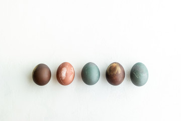 Collection of painted eggs on white stone   backround, copy space, happy easter concept. Natural colorful egg, pastel natural color.