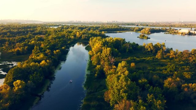 The calm clean river flows between green trees. Aerial view