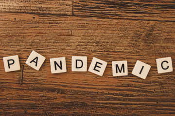 Fototapeta premium The word pandemic scattered about with tiled letters 