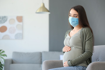 Pregnant woman wearing medical mask at home