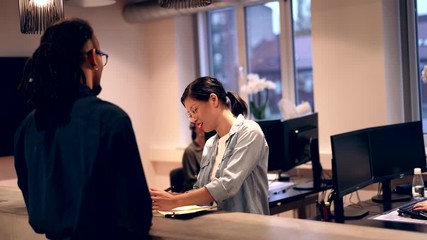 Smiling Asian
businesswoman talking with
a colleague in an office - Powered by Adobe