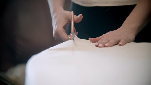 Young woman seamstress cutting the cloth