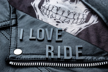 closeup to I love ride lettering over biker leather jacket and skull kerchief. motorcycle style