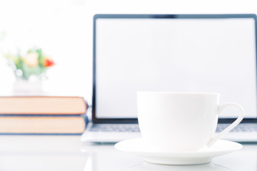 Cup of coffee with blank screen laptop computer on deck