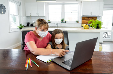 Coronavirus school closures and lockdown. Mum and bored daughter with masks studying online at home