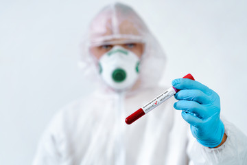 Positive COVID-19 test. Virologist in a medical mask and protective suit holds a test tube with positive blood sample