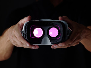 Vr glasses in man hands. Gaming device Virtual reality goggles and arm. Dark background.