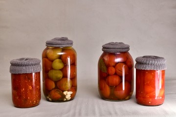Four glass jars, with textile caps that against rust, with fermented tomatoes, peppers, eggplants.