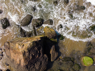 Waves in the ocean or sea breaking on stones, top view