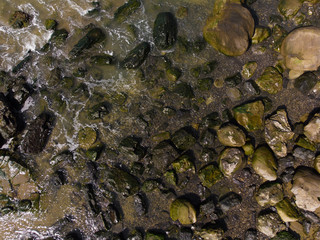 Stones on the beach with waves, ocean or sea. Texture, top view