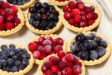 Tasty tartlets with different berries,cranberries,bilberry,blackcurrant . Berry tartlets. Cake with berries. Dessert with berries. Wooden background. Healthy food, vitamins.