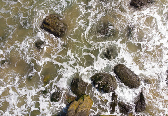 Waves on the rocks, texture, top view. Shot from a height. Pacific Ocean