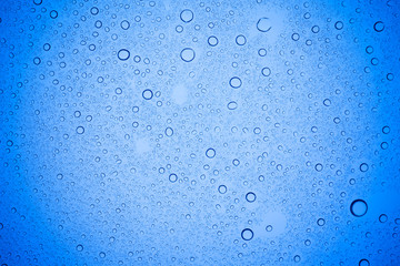 Rain droplets on blue glass background, Water drops on blue glass.