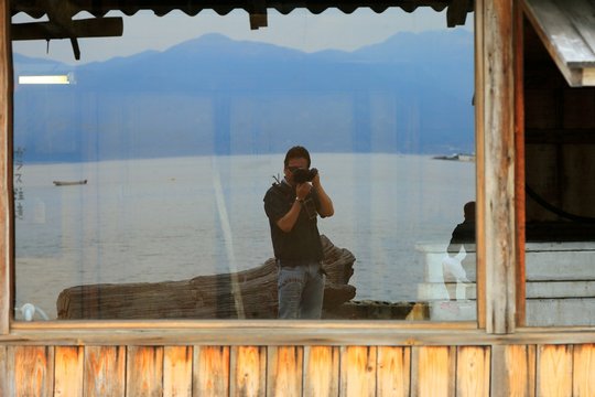 Man Photographing Self From Reflection On Glass Window