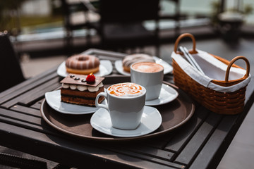cup of a fresh caramel latte with whipped cream on the table and chocolate cake.