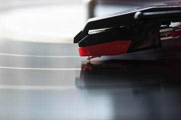 macro photograhpy to a red turntable needle and LP vinyl playing music. 