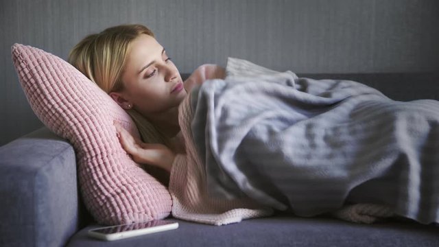 Young beautiful woman wakes up on couch in living room