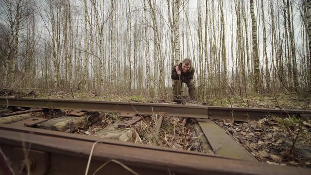 Caucasian worker swithes arrows mechanism of tracks on the railway in autumn forest