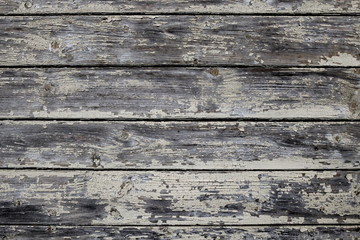 The old wooden wall with pale paint is very weathered and peeling. Rustic background.