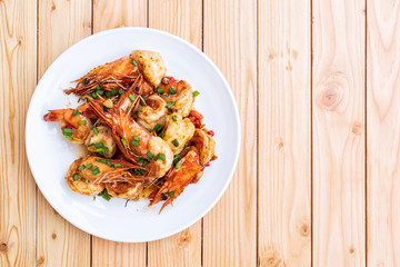 Fried stir spicy shrimps on a white dish on wooden table. Special thai food. Thai Dish Cuisine. Thai food. Top view with copy space