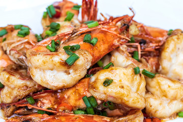 Obraz na płótnie Canvas Closeup of Fried stir spicy shrimps on a white dish on wooden table. Special thai seafood. Thai Dish Cuisine. Thai food.