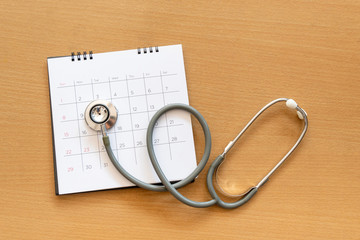stethoscope and calendar on wooden table, schedule to check up healthy concept