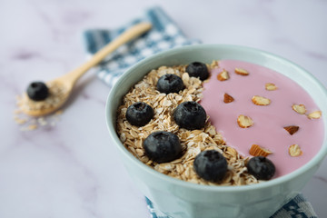 Healthy breakfast, bowl of oatmeal and yogurt with blueberries and almonds
