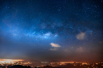 night sky with stars and milky way over a city