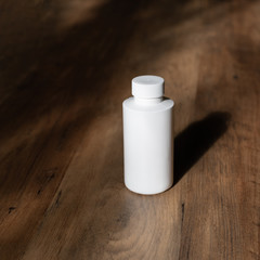 White bottle on a wooden background and shadow. Chemical Solvent Bottle with Cap