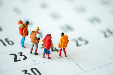Miniature people: Group of backpacker on calendar using as business trip traveler adviser agency or explorer on earth background concept.