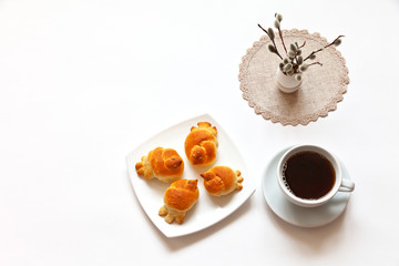 Spring still life with homemade freshly baked larks-shaped buns, a cup of hot chicory and pussy-willow twigs on a napkin with handmade lace. Palm Sunday. White background. Flat lay, copy space