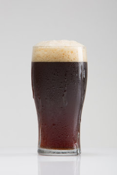 Brown Stout Beer in Frosted Glass Photographed in Studio on White Background