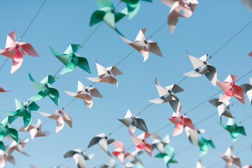 flock of colorful paper windmills flying in blue sky
