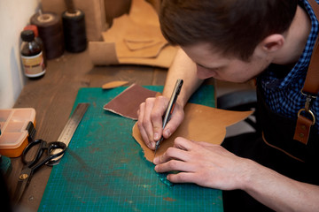 Close up of leather cutting. Cutting genuine leather with the knife. Working process of the leather craftsman. The photo can be used for needlework, handicrafts, creating leather products, hobbies
