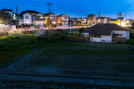 Cars Streak By Quiet Home In Suburban Neighborhood Next To Small Farm At Night