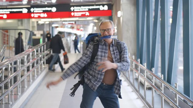 Crazy elder tourist dancing in airport with ticket in his mouth