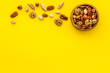 Mixed nuts in bowl - healthy snack - on yellow background top-down frame copy space